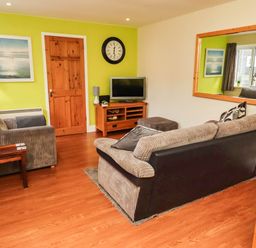 A living room with a sofa and television at Flora Cottage Beadnell
