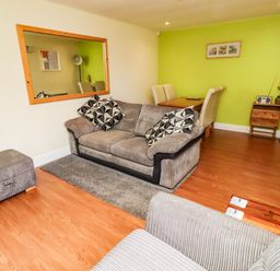A living room with a sofa and dining area at Flora Cottage Beadnell