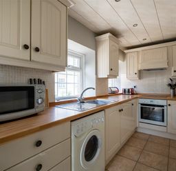 A kitchen with appliances cabinets a sink and tiled floor at The Arches in Bamburgh