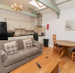 A living room with a sofa and dining area at Chiff Chaff in Lucker