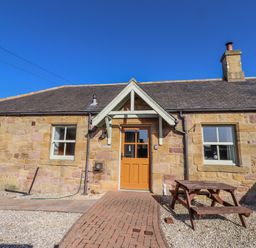 An outdoor view of a stone cottage with a brown door at Greenfinch in Lucker