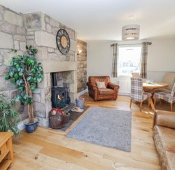 A living room with a fireplace and dining area at Greenfinch in Lucker