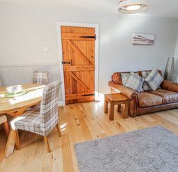 A living room with a sofa and dining table at Greenfinch in Lucker