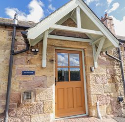 An entrance with a front door and stone wall at Rosefinch in Lucker