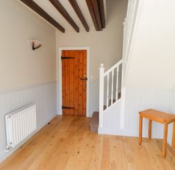 A hallway with a staircase and wooden door at Bullfinch in Lucker