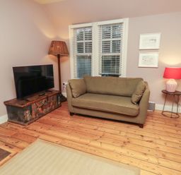 A living room with a sofa and television at Armstrong Cottages No6 Bamburgh