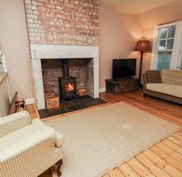 A living room with a fireplace and a sofa at Armstrong Cottages No6 in Bamburgh