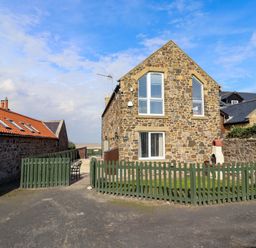 A house with a stone exterior and fenced yard at Pipistrelle in Bamburgh