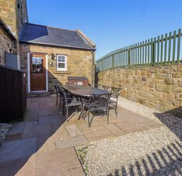 An outdoor seating area with a table and chairs at Goosander in Bamburgh