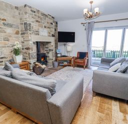 A living room with sofa and fireplace at Goosander in Bamburgh