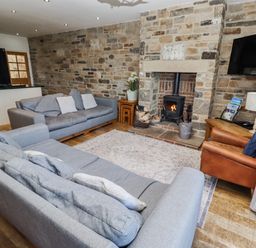 A living room with a fireplace and seating area at Goosander in Bamburgh