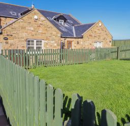A stone house with a fenced yard at Jackdaw in Bamburgh