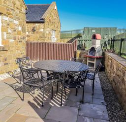 An outdoor seating area with a table and chairs at Jackdaw in Bamburgh