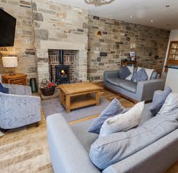A living room with a fireplace and sofas at Jackdaw in Bamburgh