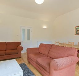 A living room with two red sofas a white coffee table a wooden dining table with chairs and a framed picture on the wall at Decked Out in Alnmouth
