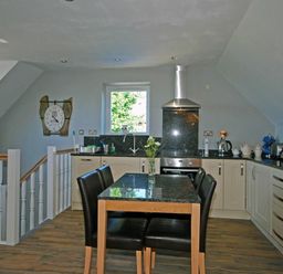 A kitchen with a dining table and chairs a stove and a window at Quarry Mews in Bamburgh