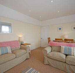 A living room with two beige sofas and a dining table with wooden chairs at Coastal Haven in Seahouses