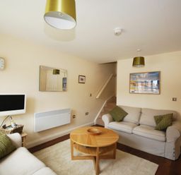 A living room with two sofas a round wooden coffee table and a wall-mounted TV at House Martins Beadnell