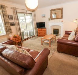 A living room with two brown leather sofas a wooden coffee table a fireplace and a TV at Arcadie in Amble
