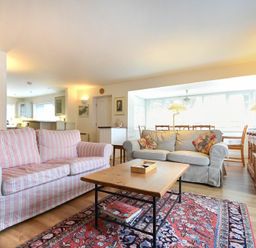 A living room with striped and plain sofas a wooden coffee table and a patterned rug at Stone Cottage in Bamburgh