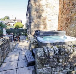 An outdoor area with a hot tub and seating at Old Mill (Lucker) Lucker