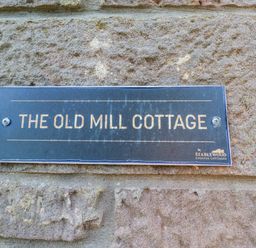 A sign for The Old Mill Cottage at Stablewood Coastal Cottages in Lucker
