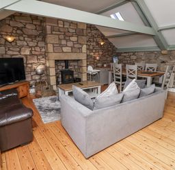 A living room with a sofa and television at Old Mill (Lucker) Lucker