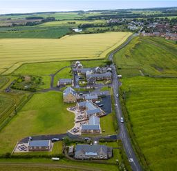 An aerial view of a rural area with houses a road and surrounding fields at Byre Cottage in Embleton