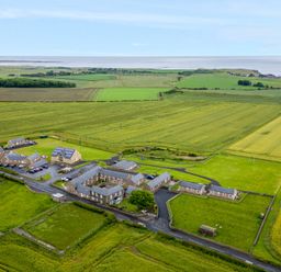 A group of buildings surrounded by green fields near the coastline at Bothy Cottage in Embleton