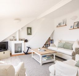 A living room with sofas coffee table television and bookshelf at The Penthouse @ No 5 in Lyme Regis