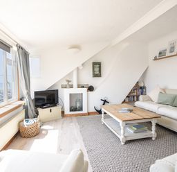A living room with sofas a wooden coffee table a television and a window overlooking a parking lot at The Penthouse @ No 5 in Lyme Regis