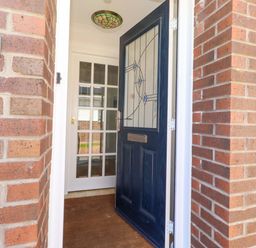 An entrance with a blue door and brick wall at 6 Westview in Embleton