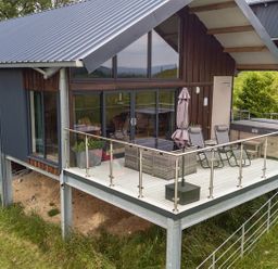 An outdoor area with decking, chairs and a hot tub at Bwncath in Garthmyl