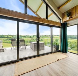 A living room with sliding glass doors leading to the deck at Bwncath in Garthmyl