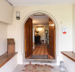 An entryway with open wooden doors leading to a tiled floor and furniture inside at Twelve Oaks Farmhouse in Teigngrace near Newton Abbot