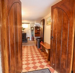 View through wooden double doors into hallway with checkerboard floor bench painting and grandfather clock at Twelve Oaks Farmhouse in Teigngrace near Newton Abbot