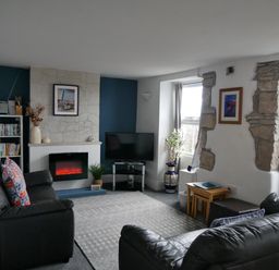 A living room with two black leather sofas a fireplace a television and a bookshelf at Fisherman's Cottage in Southwell