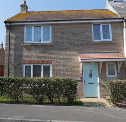 A front view of a two-story brick house with a blue door and hedges at Cliffwalk Cottage in Southwell