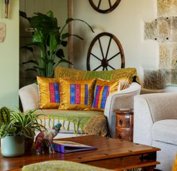 A living room with a wooden coffee table plants and colorful cushions on sofas at The Lodge in Hartlington near Grassington