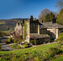An old stone house with a garden and trees on a hillside at Kail House in Grassington