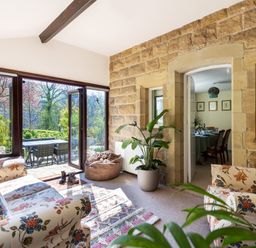 A sitting area with floral sofas and a bean bag near large glass doors opening to a patio at Kail House in Grassington