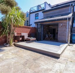 A garden with decking and seating area at Ty Haul Rhosneigr