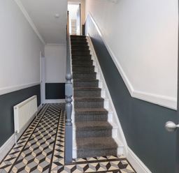 A hallway with a staircase and patterned flooring at Ty Haul in Rhosneigr