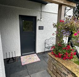 A door with a doormat and flowers at How Hill Farm Cottage in Greystoke