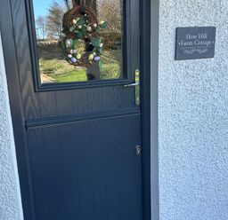 A door with a wreath and a sign at How Hill Farm Cottage in Greystoke