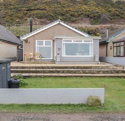 A bungalow with patio chairs and steps leading to a grass garden at The Chalet in Coulderton near Egremont Cumbria