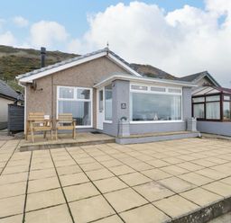 A single-story house with a tiled patio and two wooden chairs at The Chalet in Coulderton near Egremont Cumbria