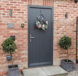 Front door with floral wreath and potted plants on either side at Bracken Cottage in Pocklington