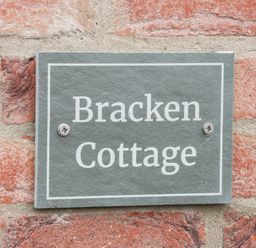A stone plaque with the words Bracken Cottage fixed to a red brick wall at Bracken Cottage in Pocklington