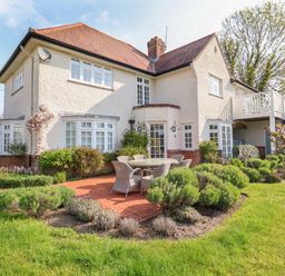 A two story house with a red tiled roof white windows and a garden with outdoor furniture at Halsey in Walberswick